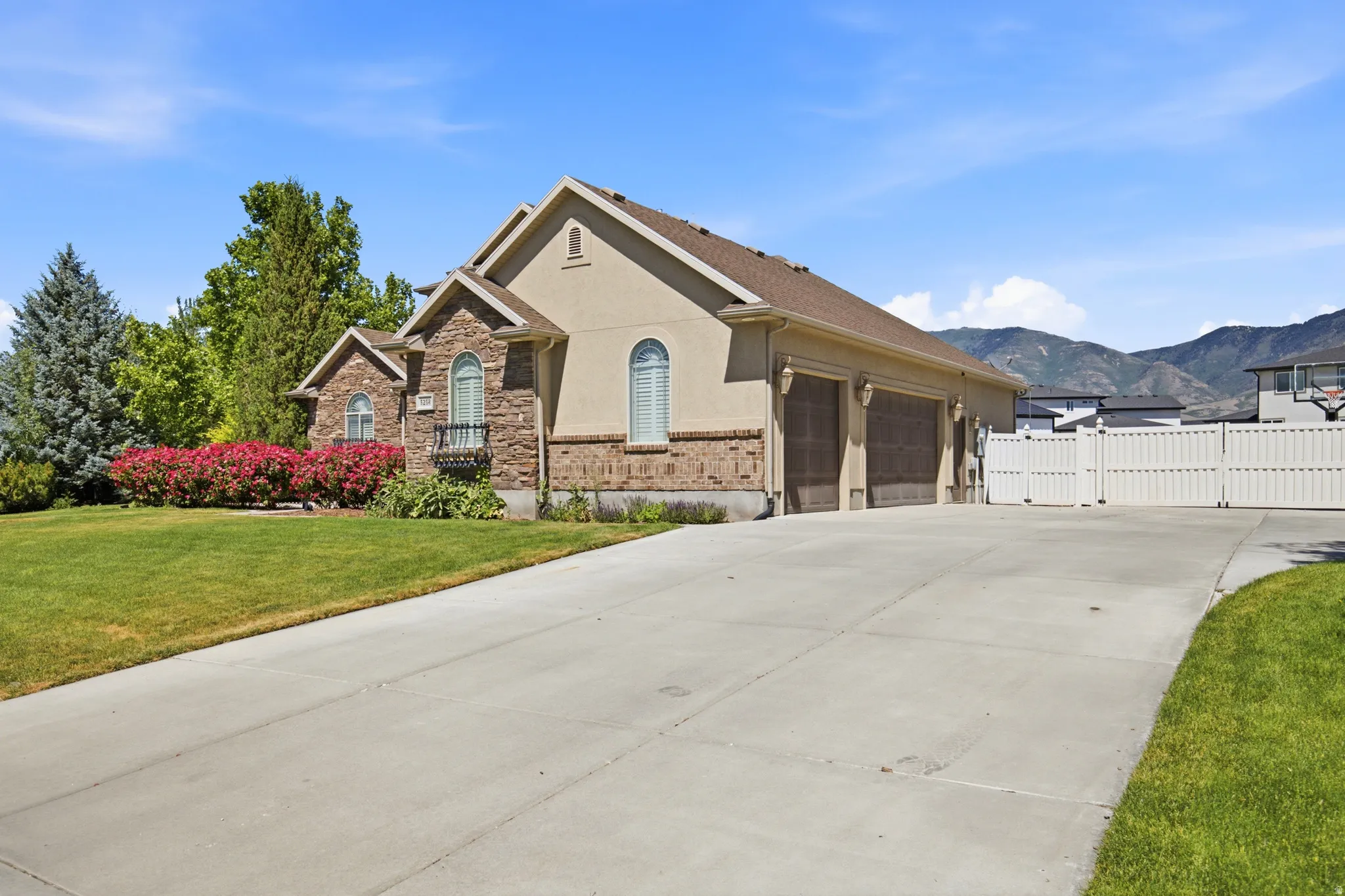Stucco and stone exterior featuring arched windows, a multi-car garage, and a concrete driveway