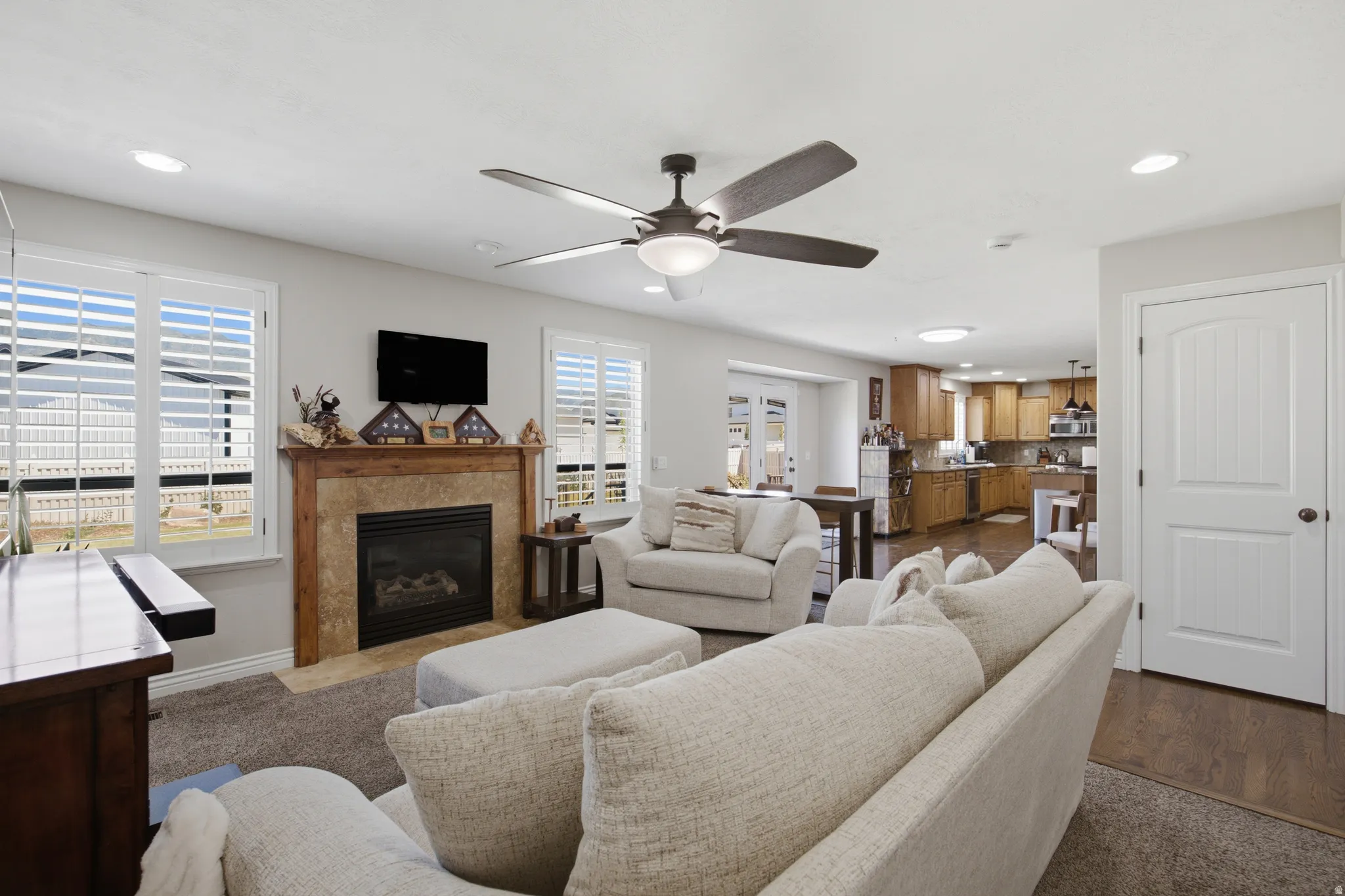 Open-concept living area with a gas fireplace featuring a stone surround and wood mantel