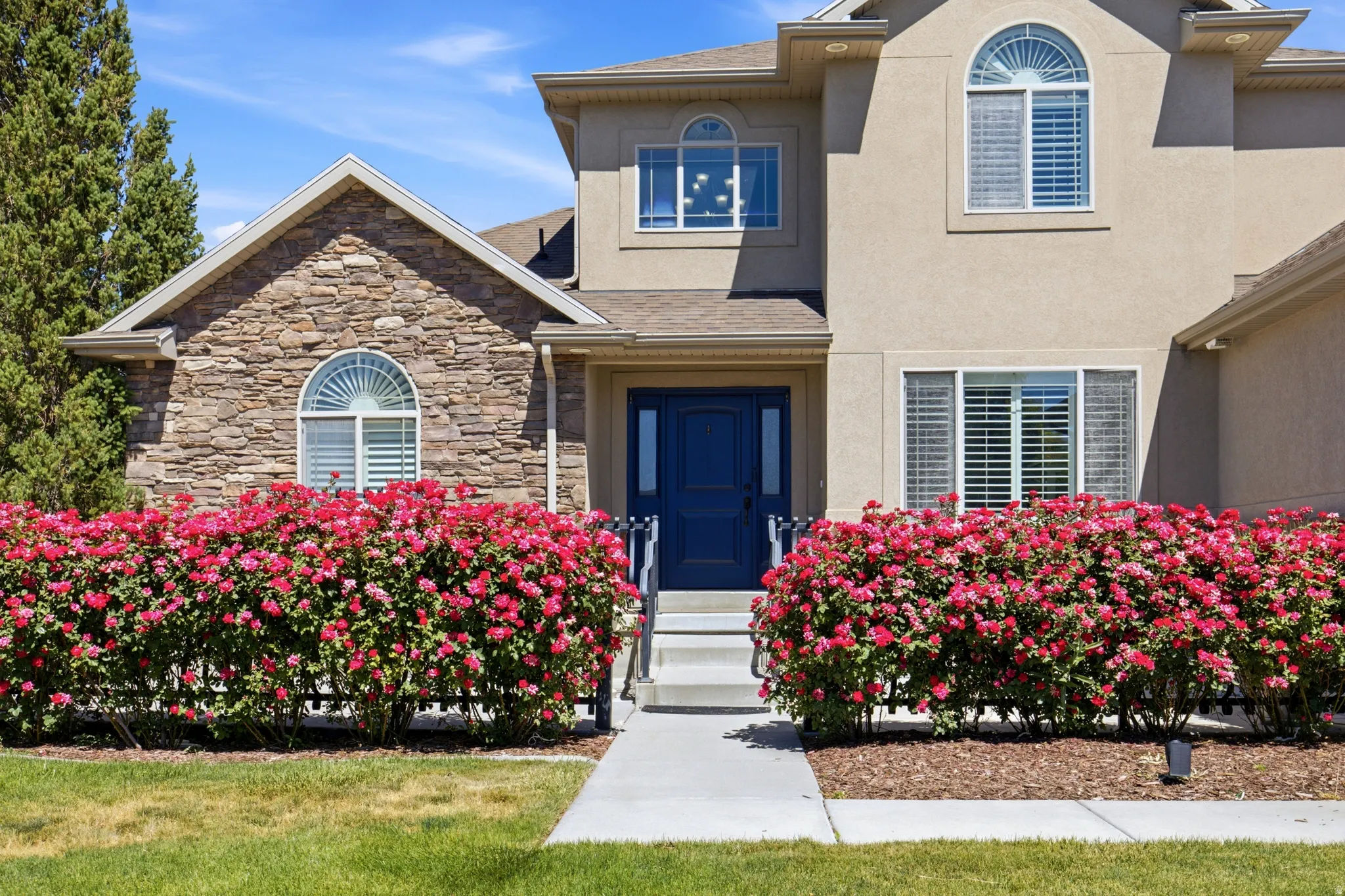 Stucco and stone facade with a prominent arched window and a dark blue entry door