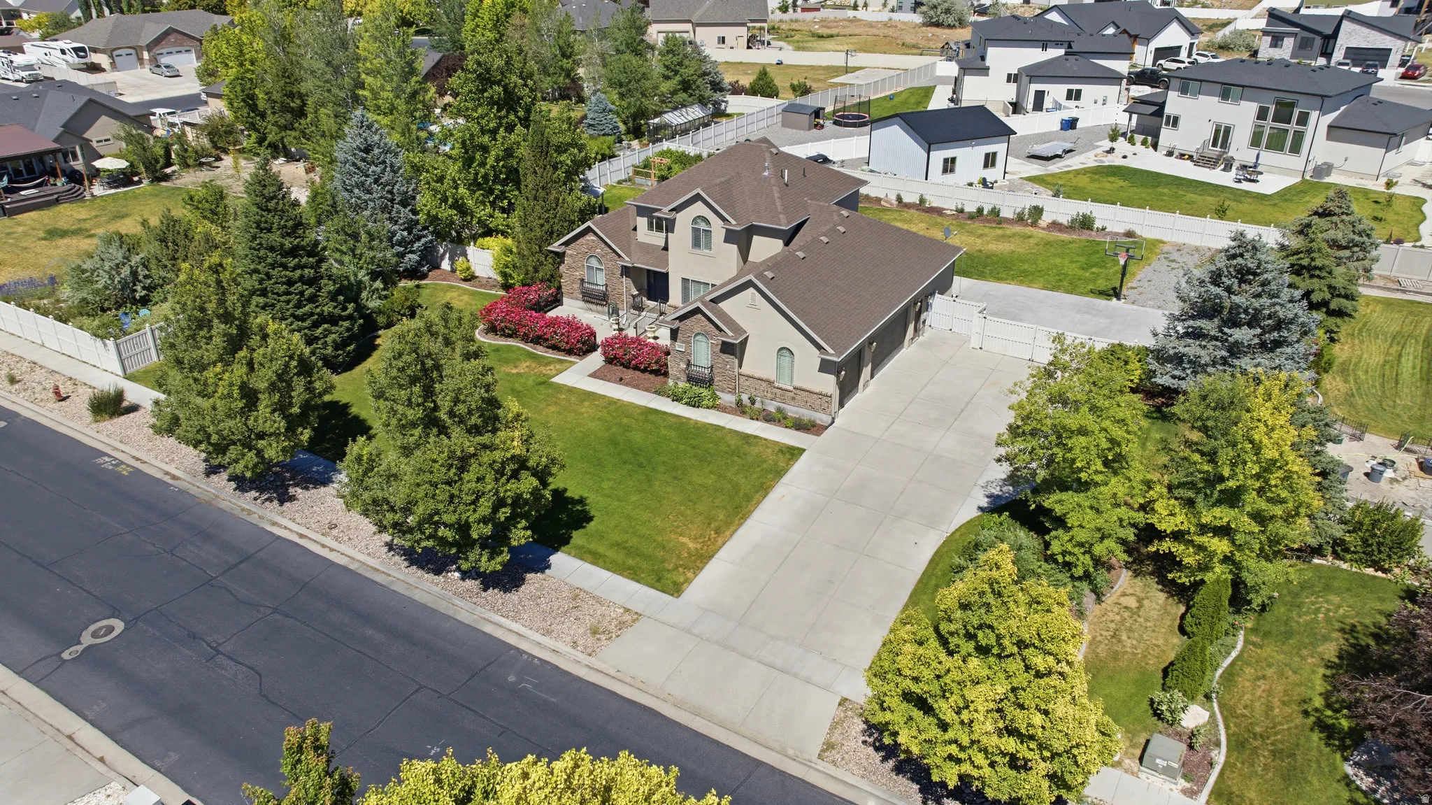 Two-story residence featuring a stone and siding exterior, a multi-car driveway, and a manicured front lawn