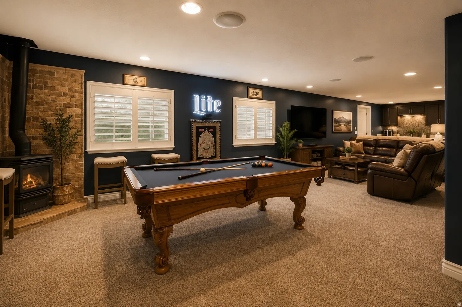 Open-concept recreation room featuring a corner wood-burning stove with a brick surround, light-colored carpeting, and dark accent walls
