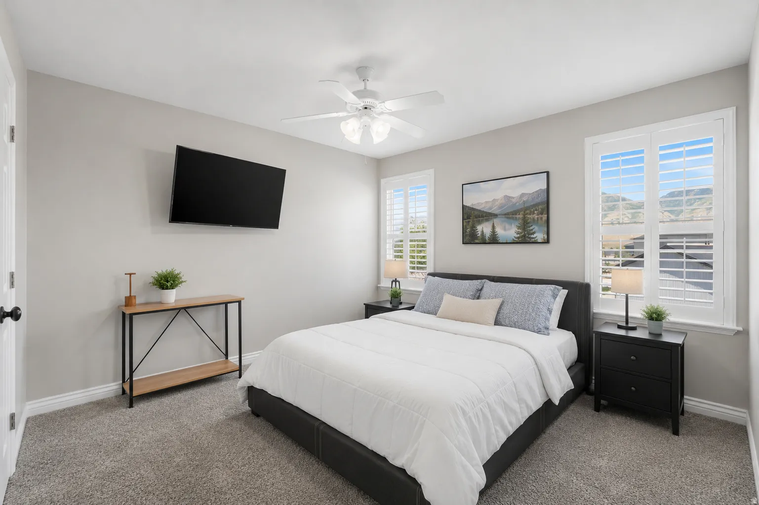 Bedroom featuring twin windows with white plantation shutters, gray carpeting, and a ceiling fan