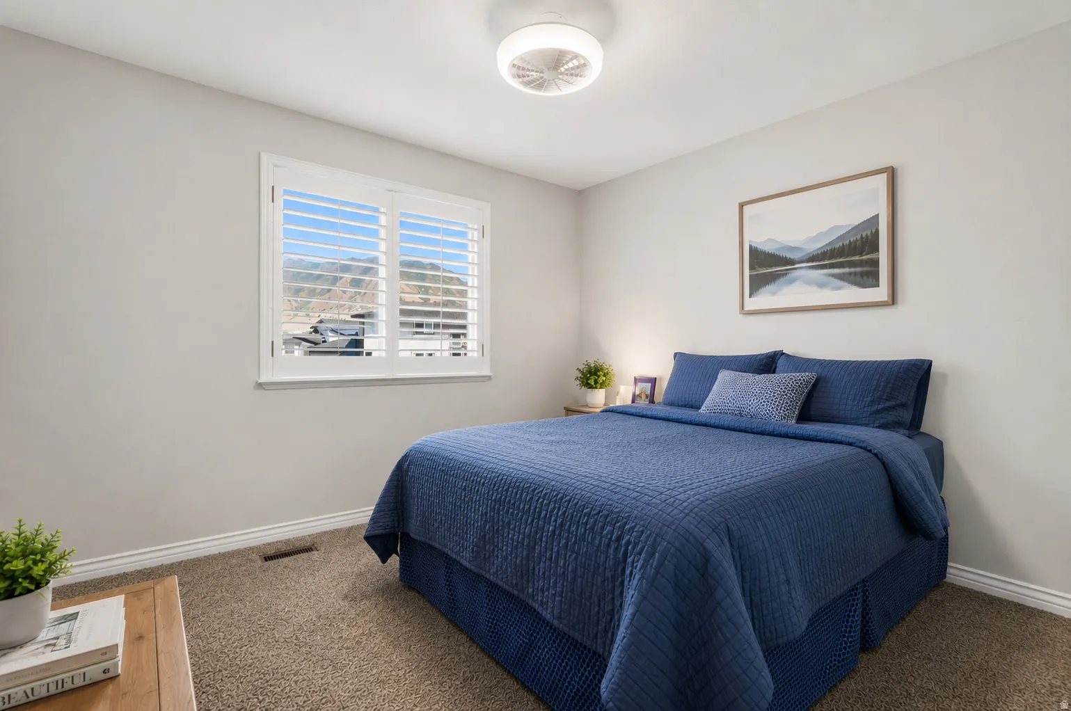 Carpeted bedroom featuring a window with plantation shutters, mountain scenery, light gray walls, and white trim