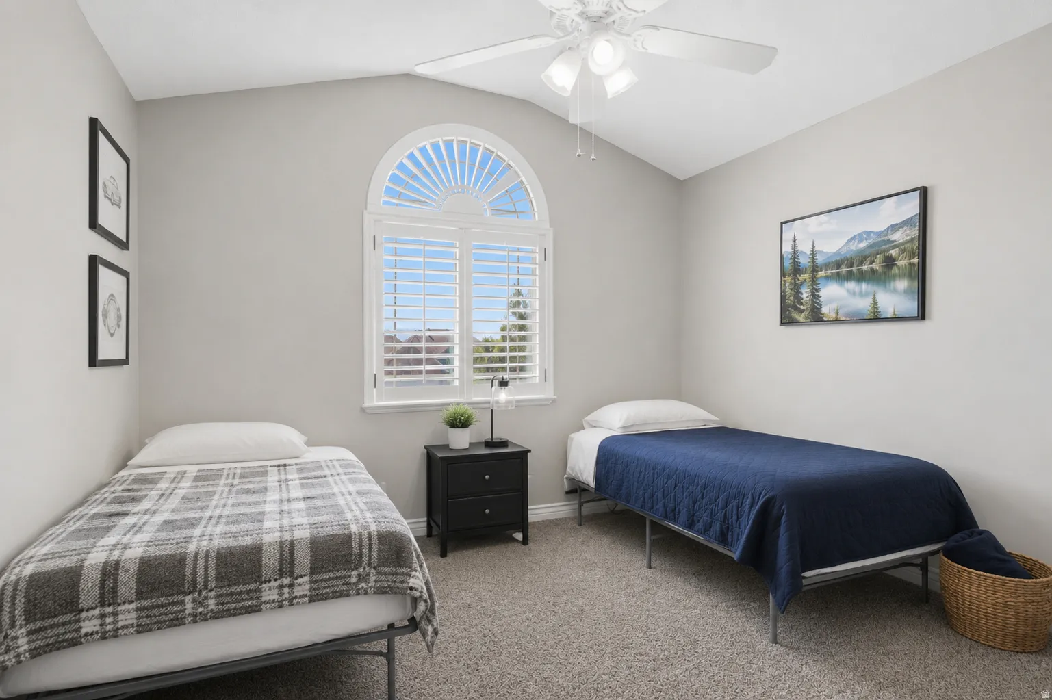 Vaulted ceiling room featuring a large arched window with plantation shutters, ceiling fan, and grey carpet flooring