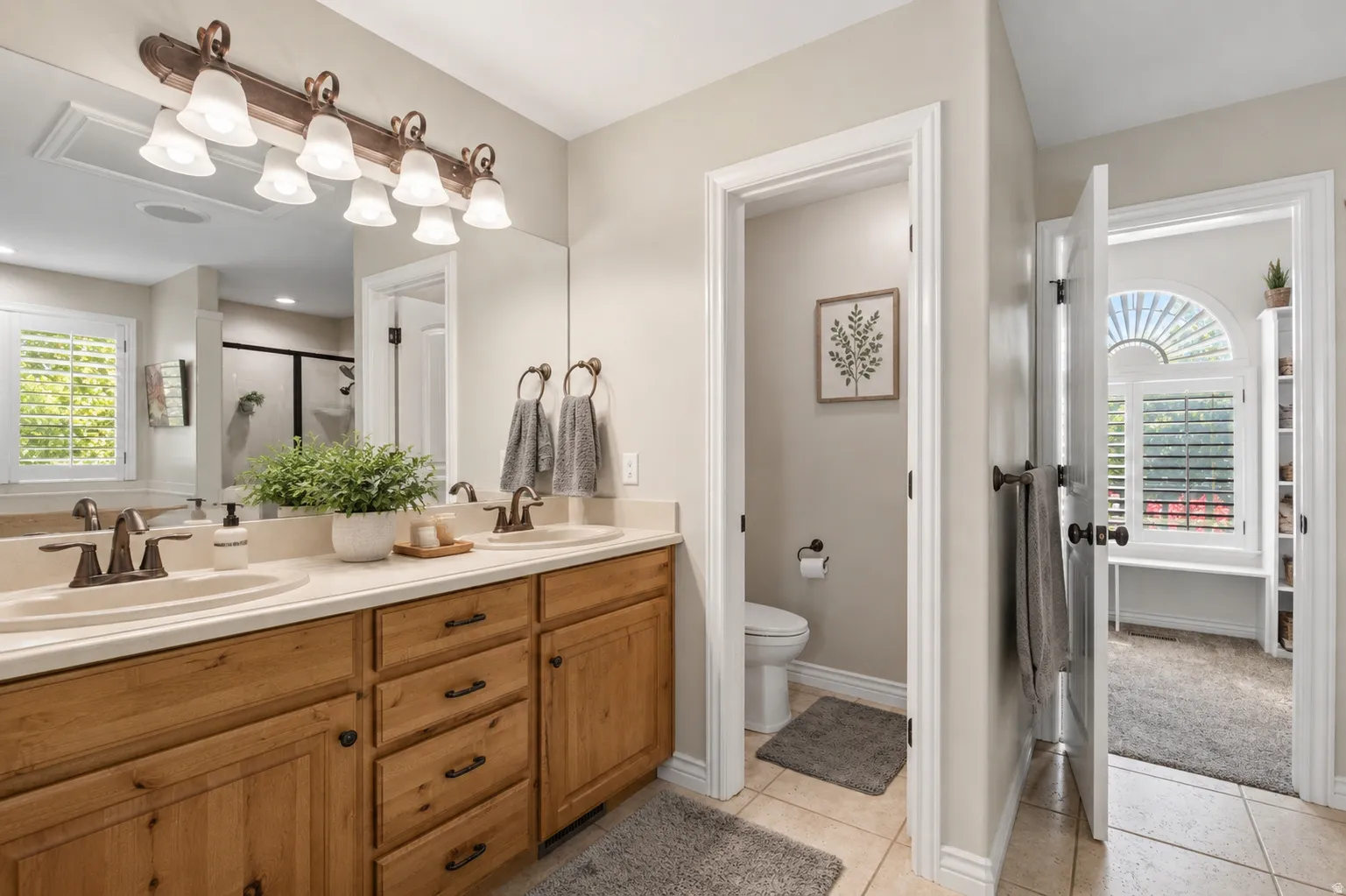 Double vanity with light wood cabinetry, dual undermount sinks, and bronze-finish fixtures