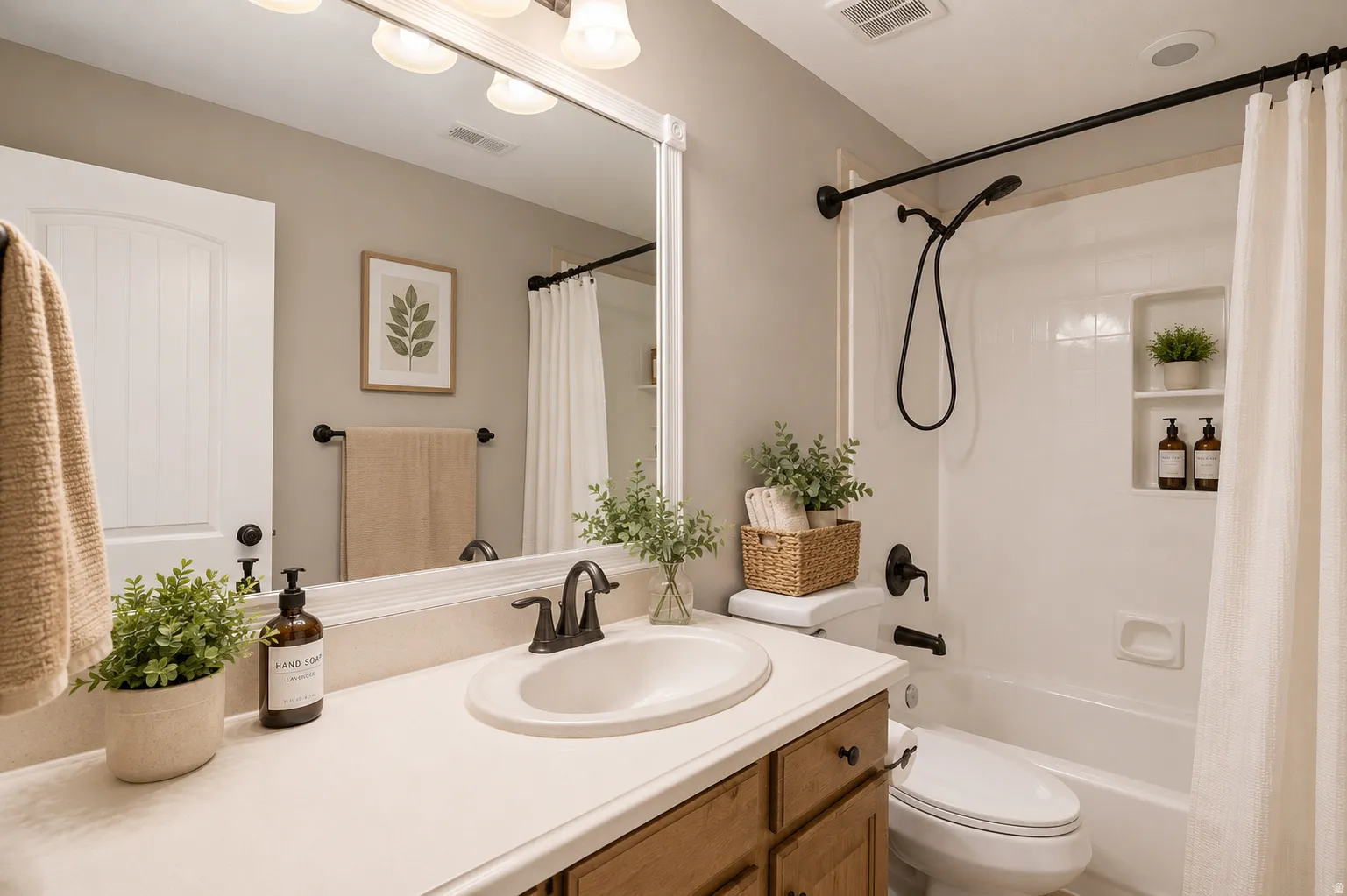 Bathroom featuring a wood-finish vanity with an integrated sink, a large wall mirror, and a full bathtub with a shower