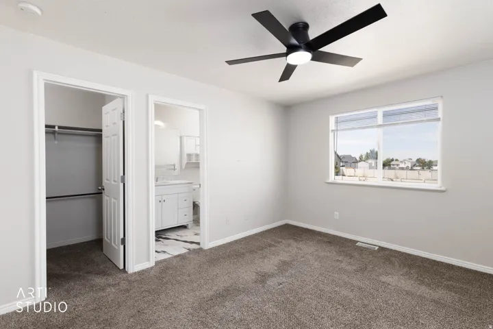 Spacious room featuring carpet flooring, a ceiling fan with integrated lighting, a window with horizontal blinds, and access to a closet with built-in shelving