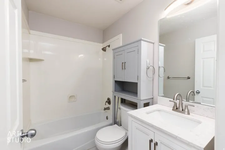White vanity with a stone-finish countertop and undermount sink