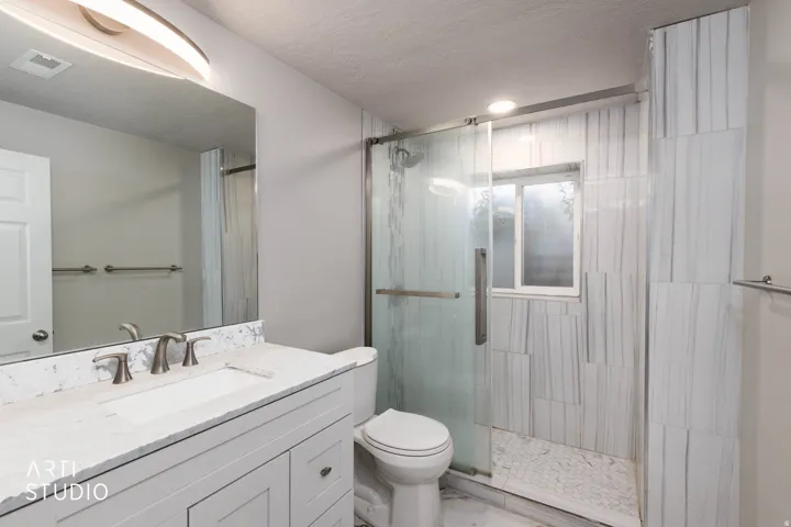 White vanity with an integrated rectangular sink, wall-mounted mirror, brushed nickel faucet, and marble-look countertop