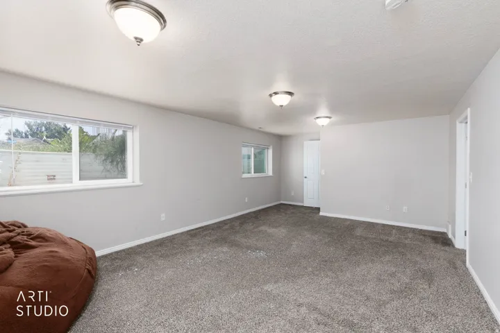 Recessed lighting fixtures illuminate a spacious room featuring carpeted flooring and light-toned walls