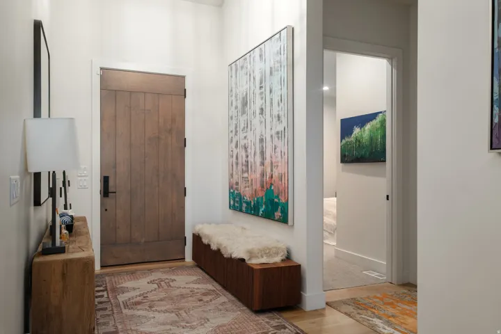Entryway featuring a solid wood plank door with matte black hardware, light wood-finish flooring, and white baseboards