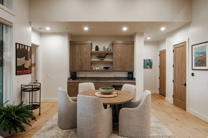Built-in wet bar featuring upper and lower cabinetry, open shelving, and a stone countertop