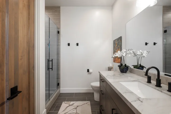 Bathroom featuring a single vanity with a white countertop, undermount sink, and matte black faucet