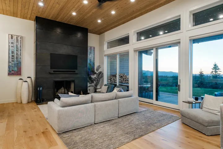 Spacious living area featuring a floor-to-ceiling fireplace with an integrated media niche, wood-finish flooring, and a wood-paneled ceiling