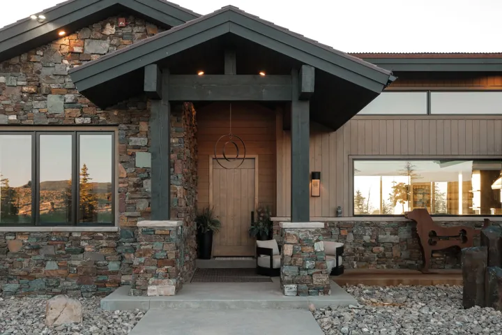 Stone veneer and horizontal siding exterior featuring a covered entry