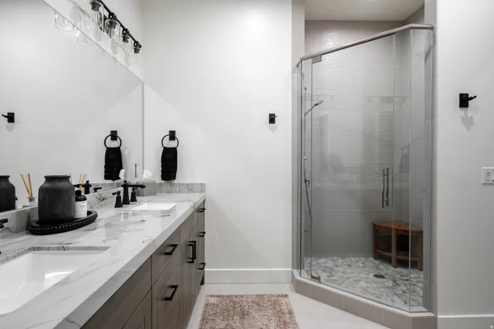 Dual vanity with a white marble-finish countertop, undermount sinks, and dark wood-finish cabinetry