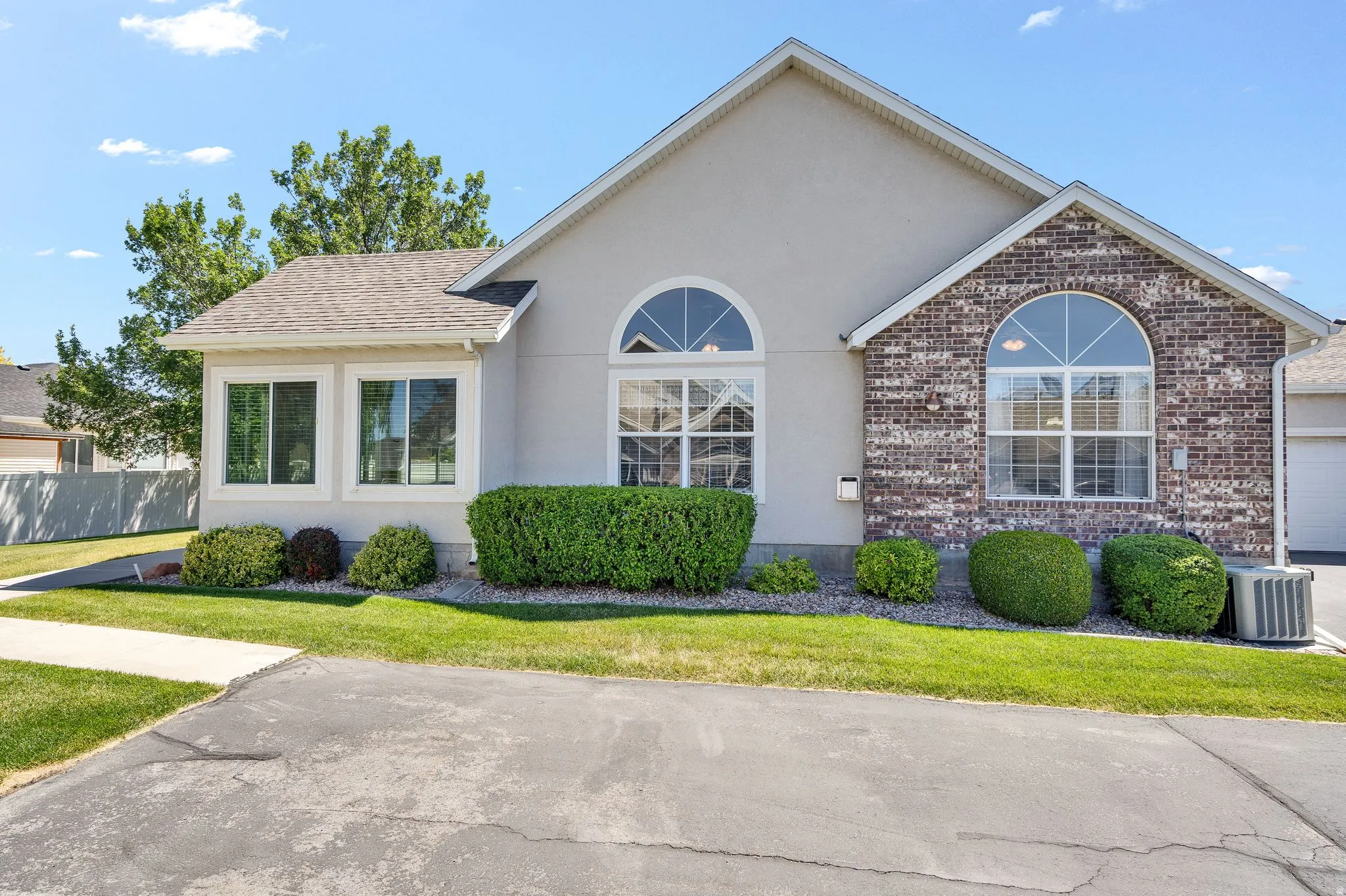 Exterior facade featuring a combination of stucco and brick finishes, arched transom windows, a bay window, and a gabled roofline