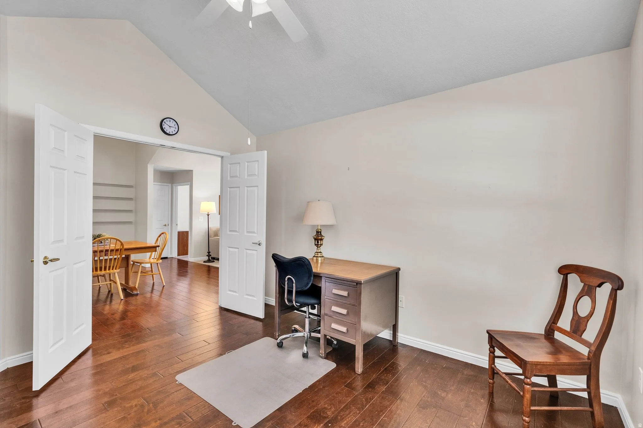 Room with wood-finish flooring, vaulted ceiling, and a ceiling fan