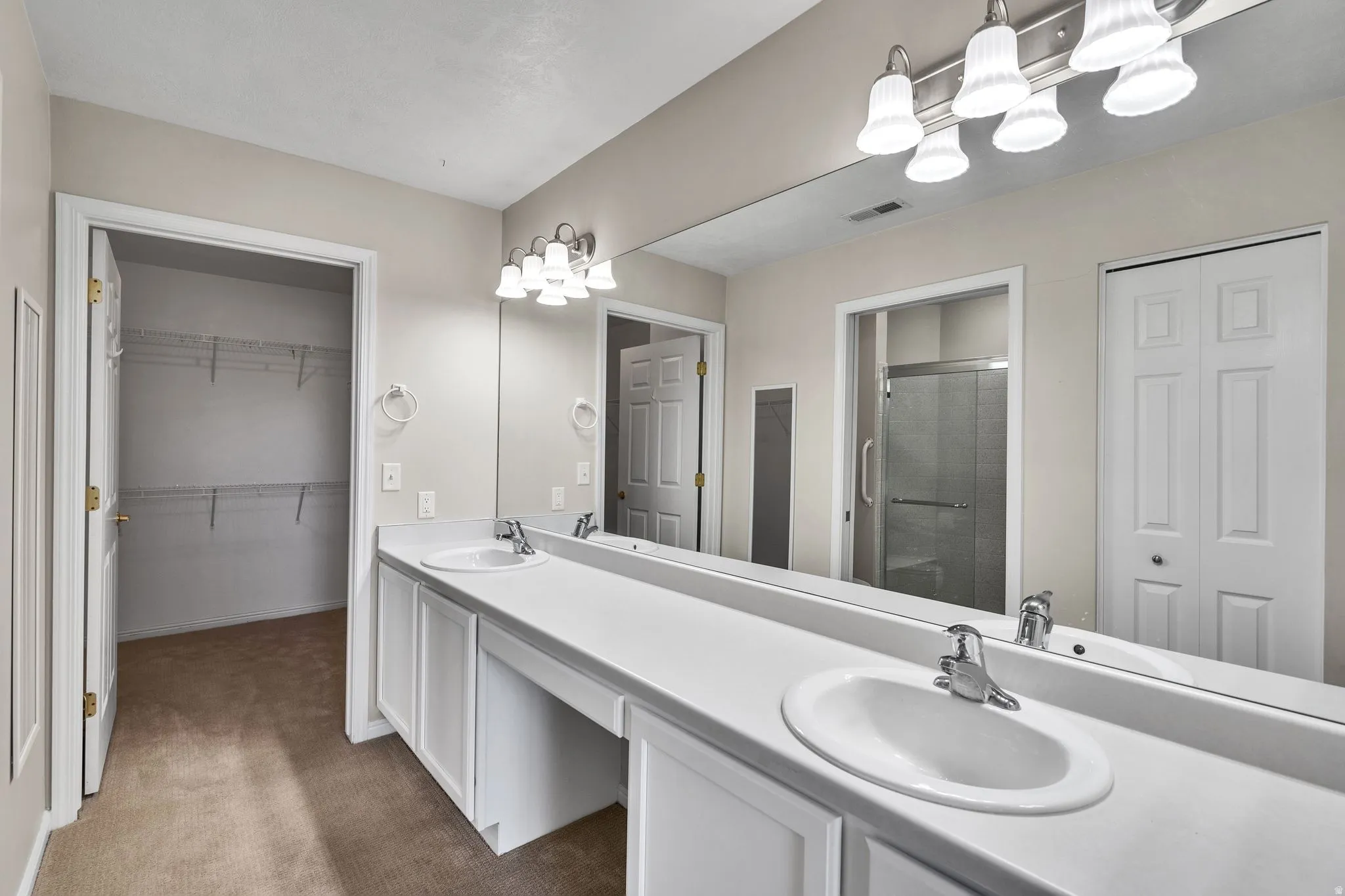 Primary Bathroom featuring a long vanity with dual sinks, overhead vanity lighting, and a large wall-mounted mirror