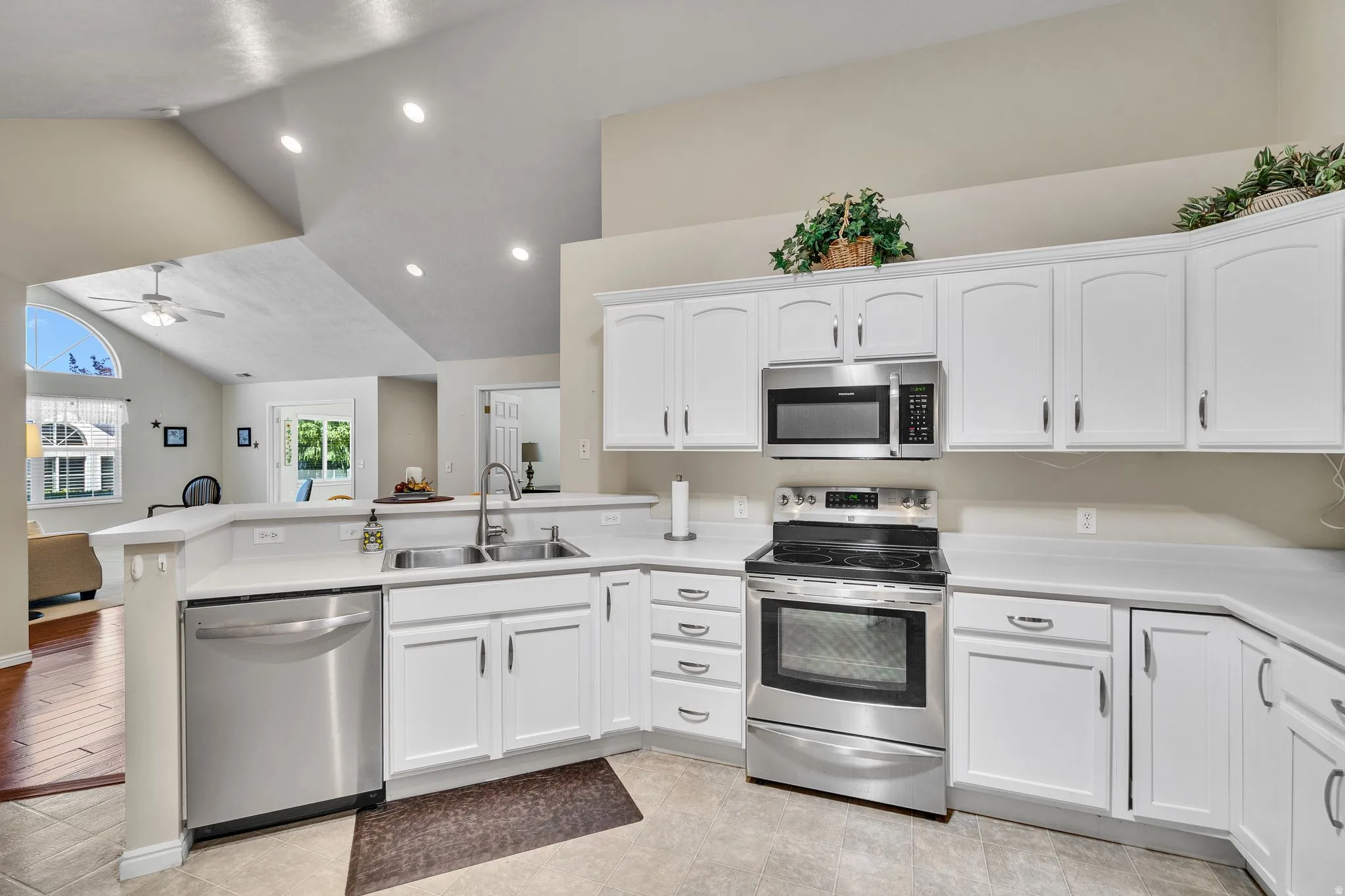 Kitchen with white cabinetry, stainless steel appliances, a double basin sink, and light-toned countertops