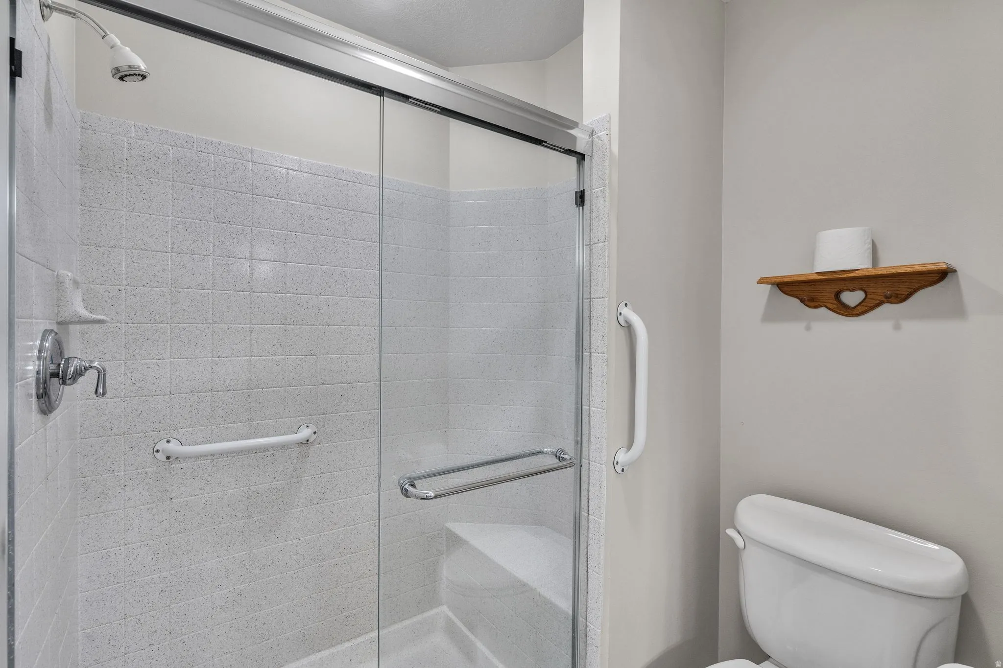 Primary Bathroom Shower enclosure with frosted glass panels, white tiled walls, chrome fixtures, and integrated grab bars