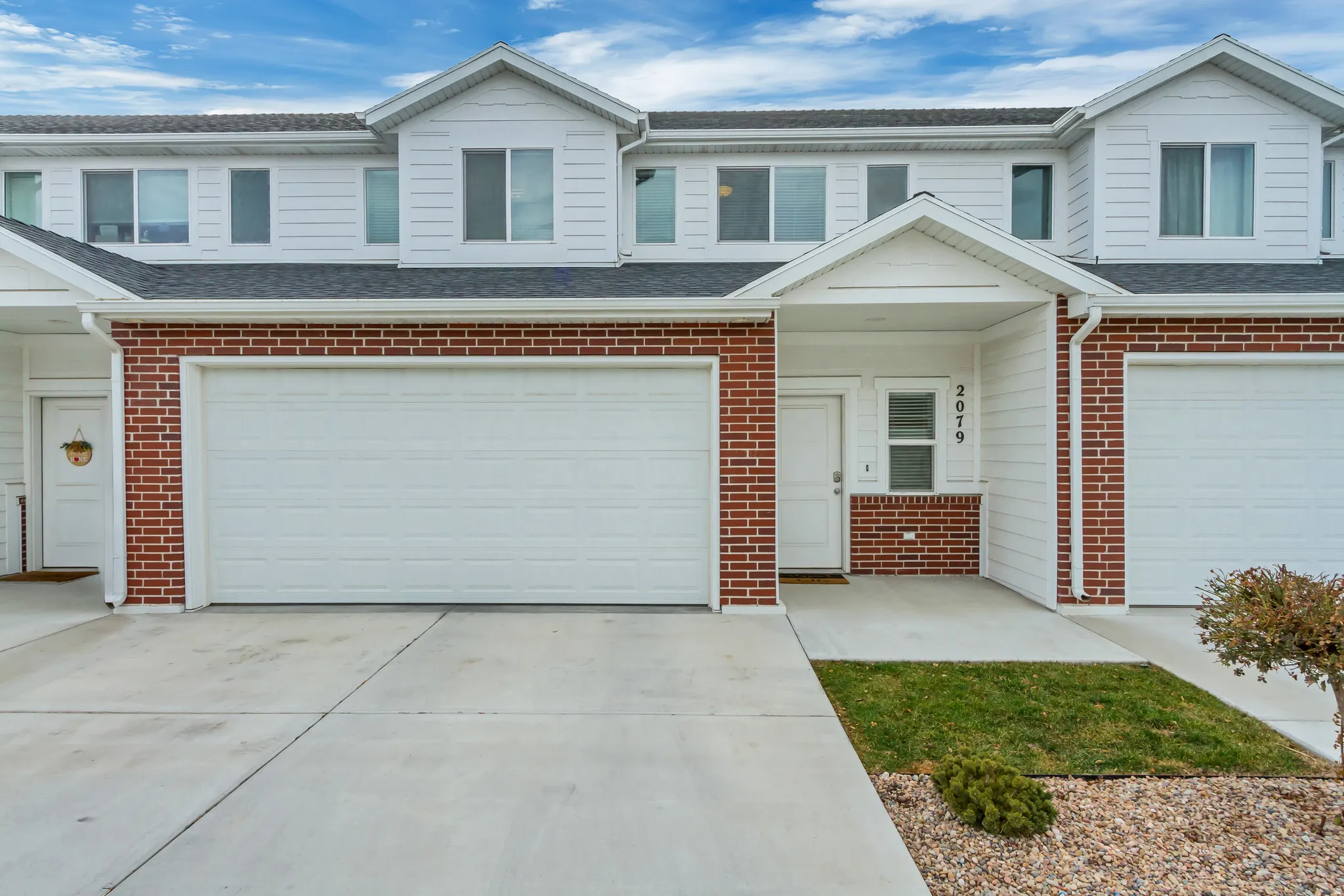 Townhome exterior featuring white siding and red brick accents