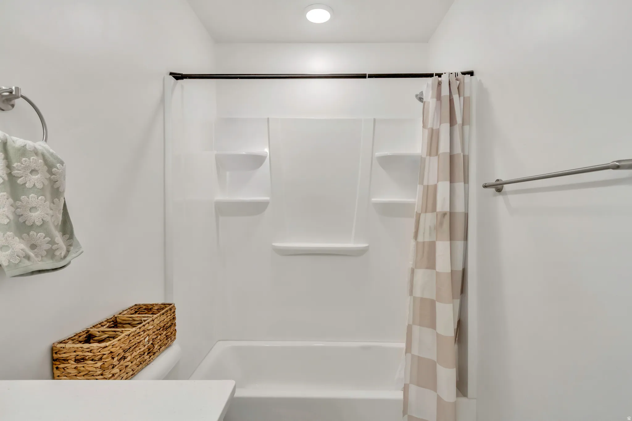 Bathtub and shower combination featuring an integrated white surround with built-in shelving