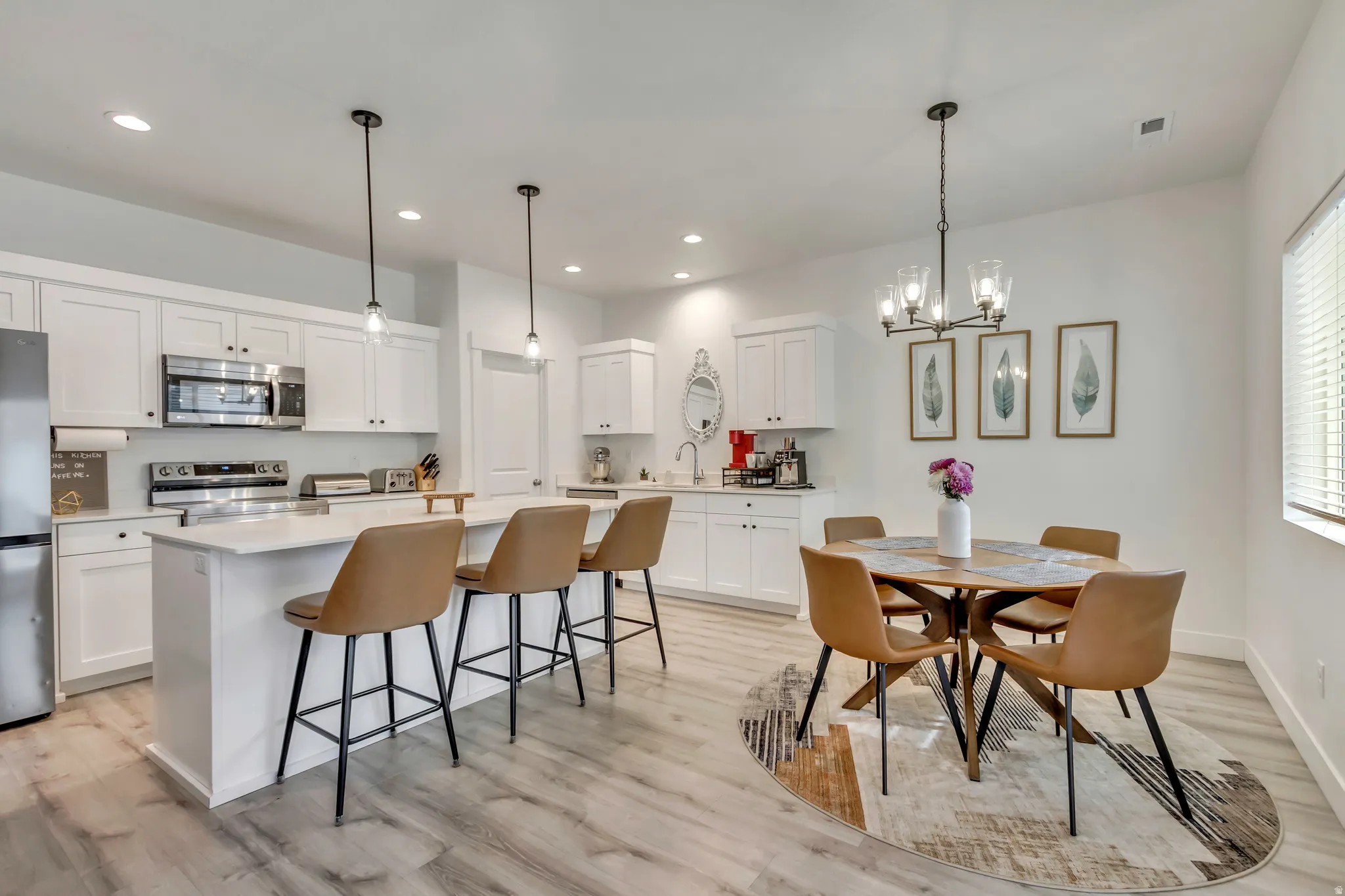 Kitchen featuring white cabinetry, stainless steel appliances, a white island with pendant lighting, and wood-finish flooring