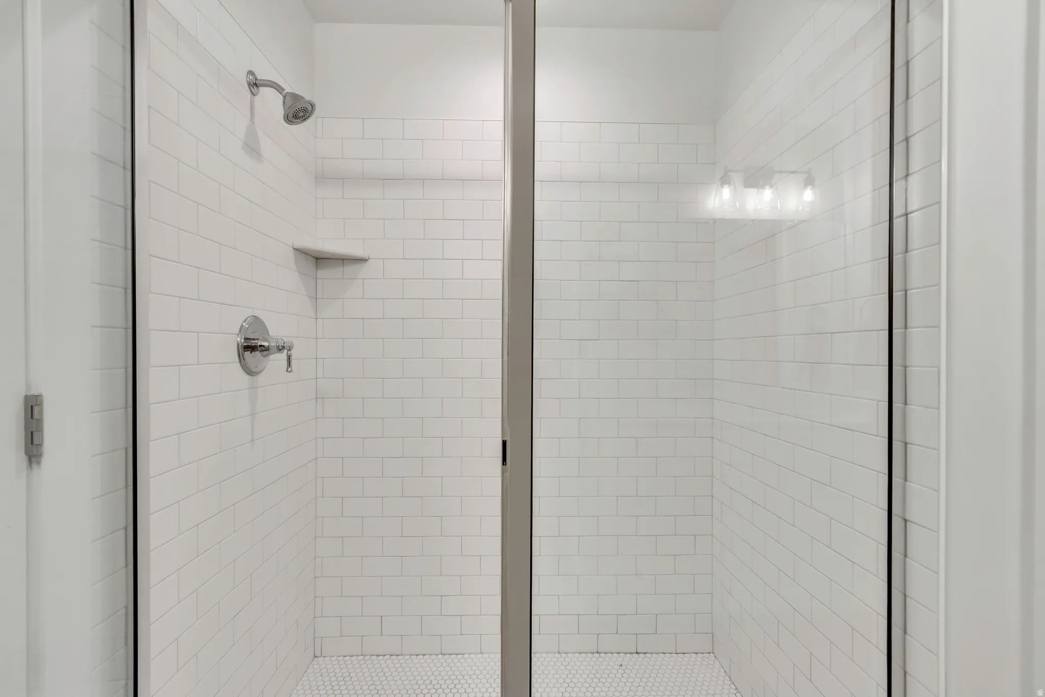 Walk-in shower featuring subway tile walls, a built-in corner shelf, and a hexagonal tile floor