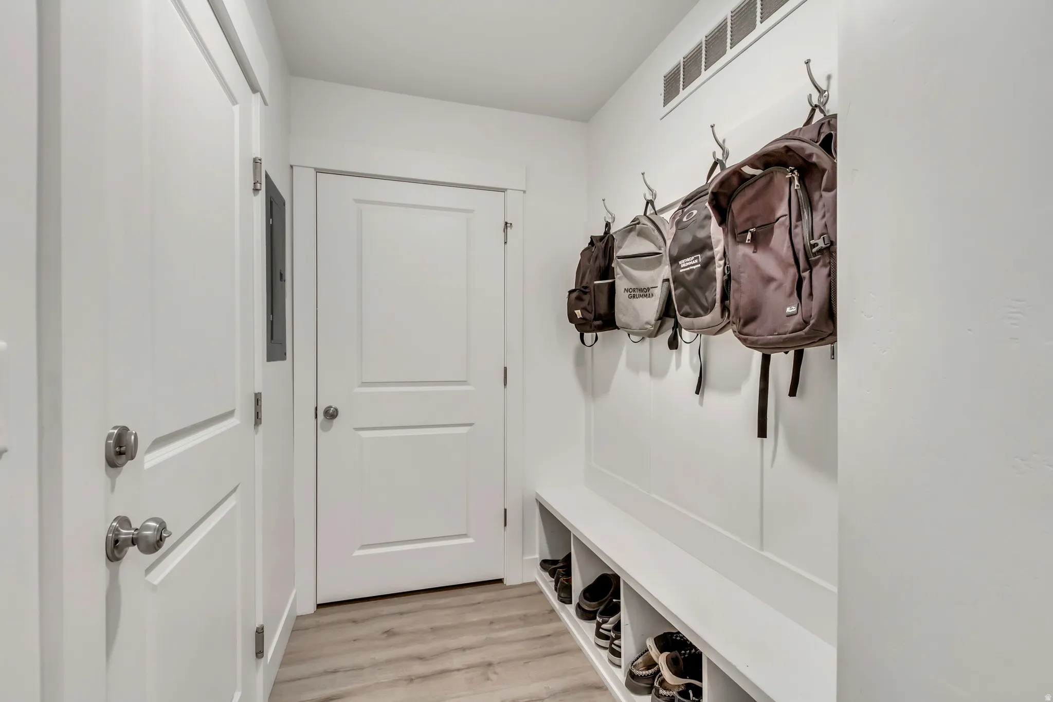 Entryway featuring a built-in bench with integrated shoe cubbies, wall-mounted coat hooks, and light wood-finish flooring