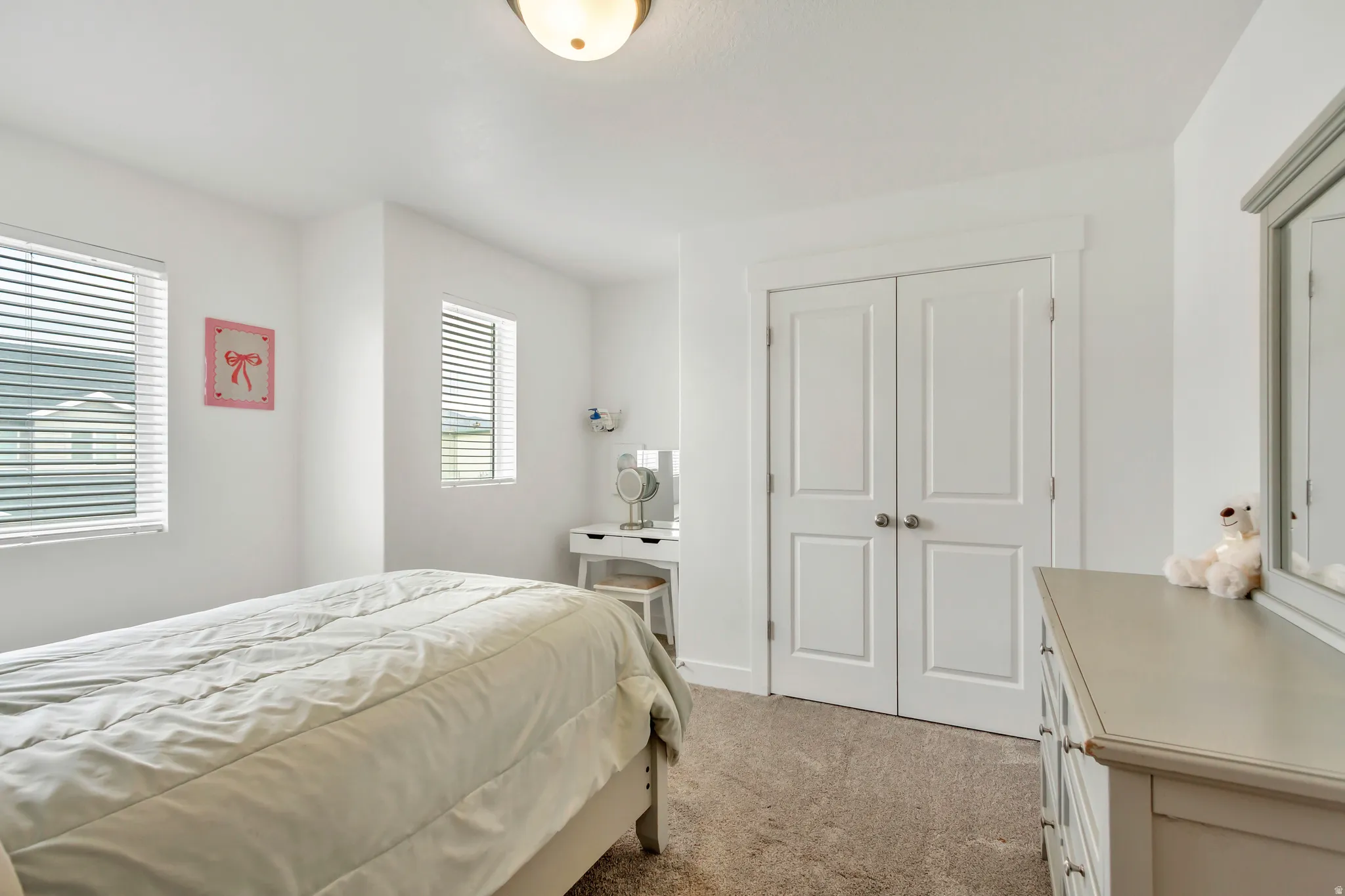 Carpeted room featuring multiple windows with blinds, a double-door closet, and a ceiling-mounted light fixture
