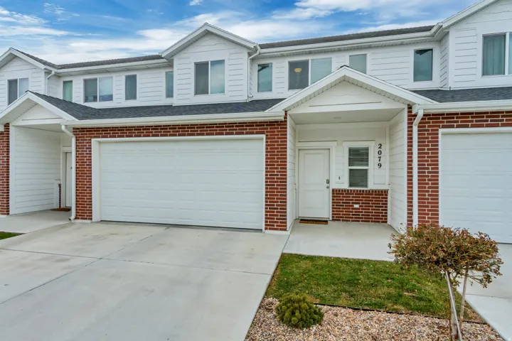 Multi-level townhouse exterior featuring a brick and siding facade, a covered entry, an attached garage, and a concrete driveway