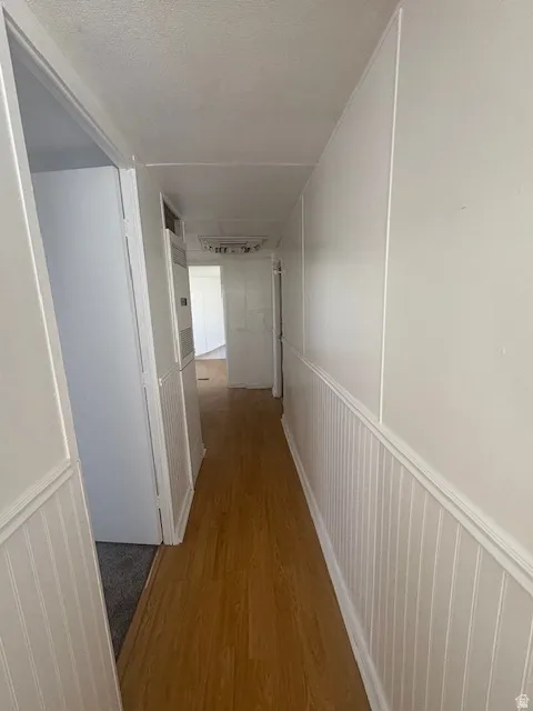 Hallway featuring wood-finish flooring, white beadboard wainscoting, and white walls