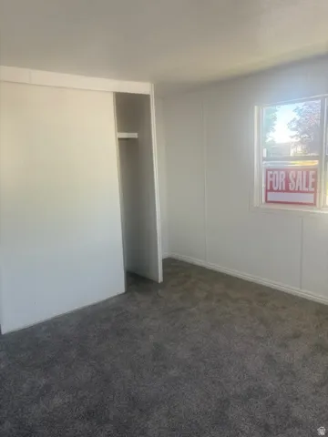 Carpeted room featuring a white sliding closet door and a single window