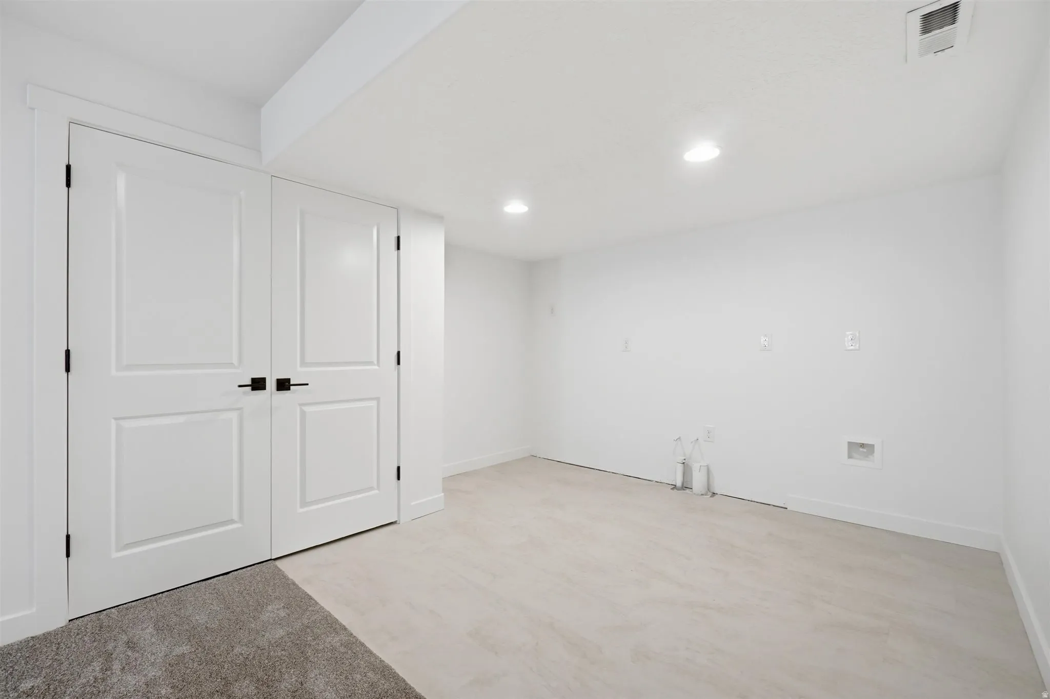 Bright, open room featuring recessed lighting, light-toned flooring, and white walls