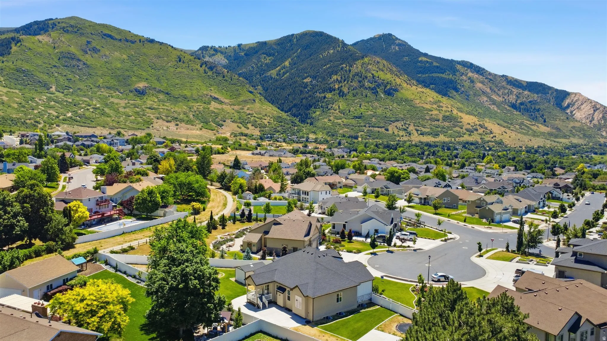 Expansive neighborhood featuring varied architectural styles and mature landscaping, set against a mountainous backdrop