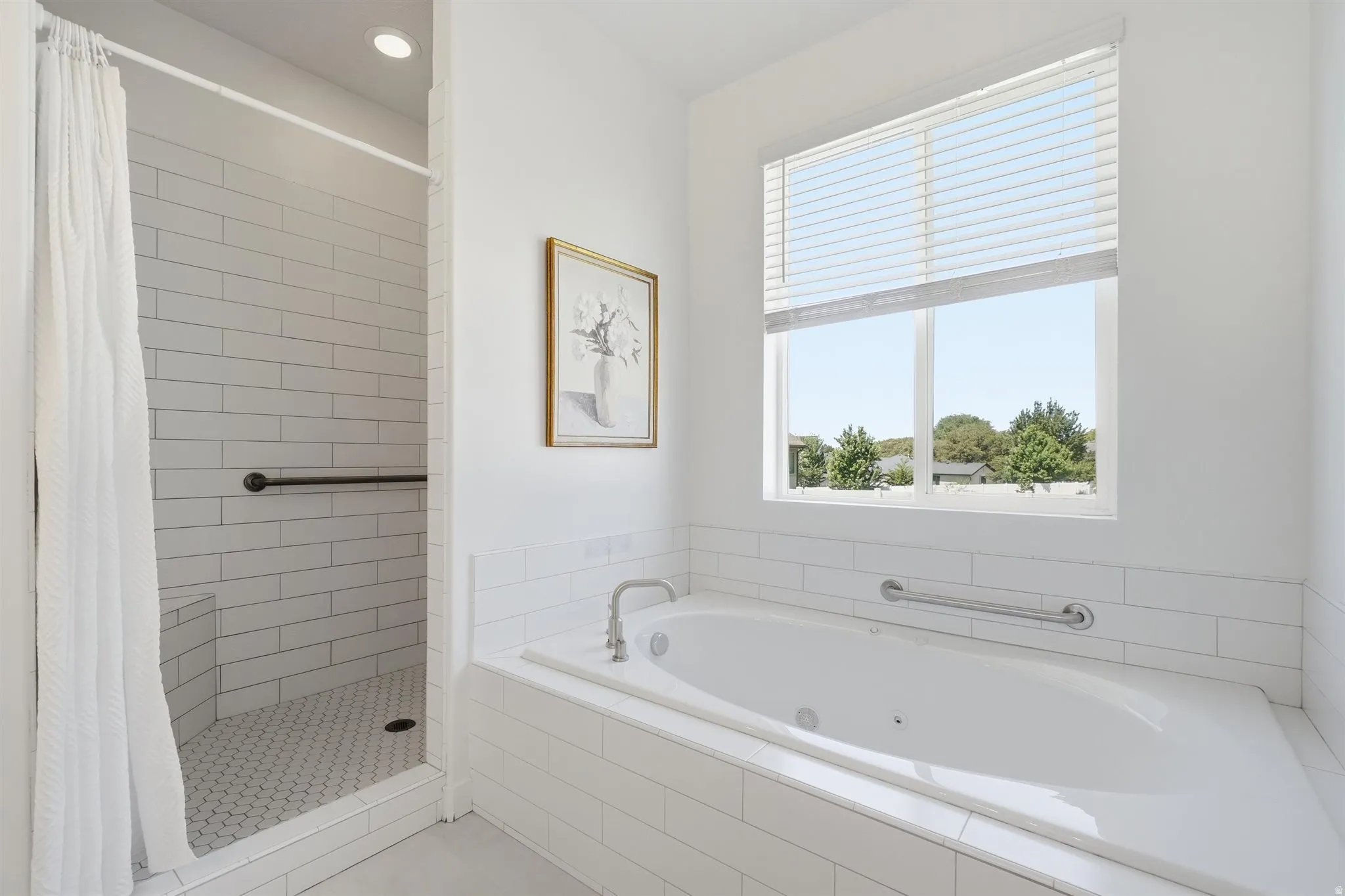 Bathroom featuring a built-in soaking tub with a tiled surround, a large window with blinds, and a tiled shower with a built-in bench
