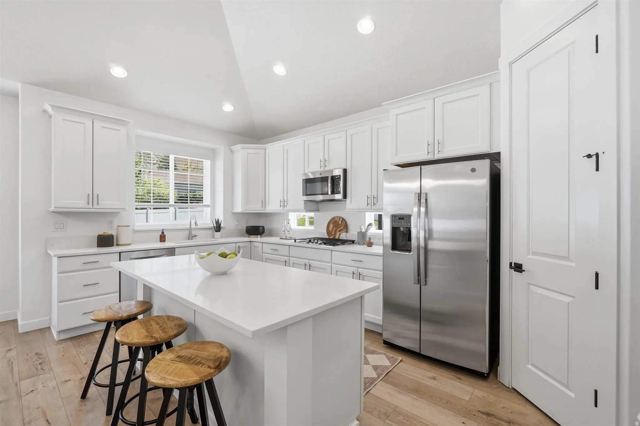 Modern kitchen featuring a central island, white cabinetry, stainless steel appliances, recessed lighting, and wood-finish flooring