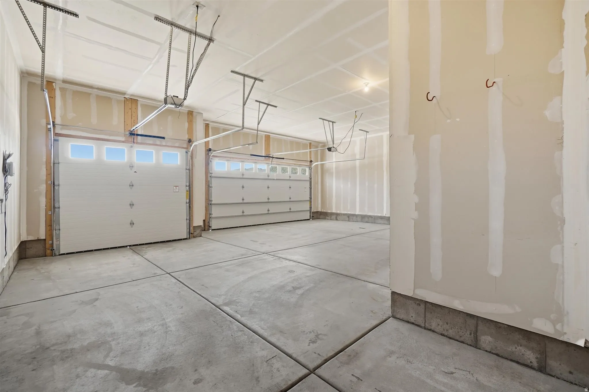 Spacious multi-car garage featuring two white sectional garage doors with upper window panels