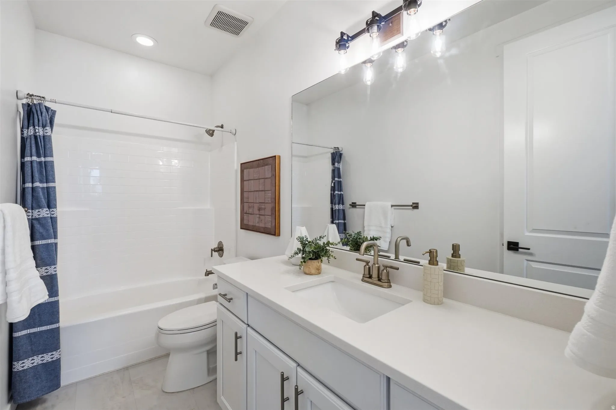 Contemporary bathroom featuring a single vanity with light-colored cabinetry, a spacious countertop, and an undermount sink