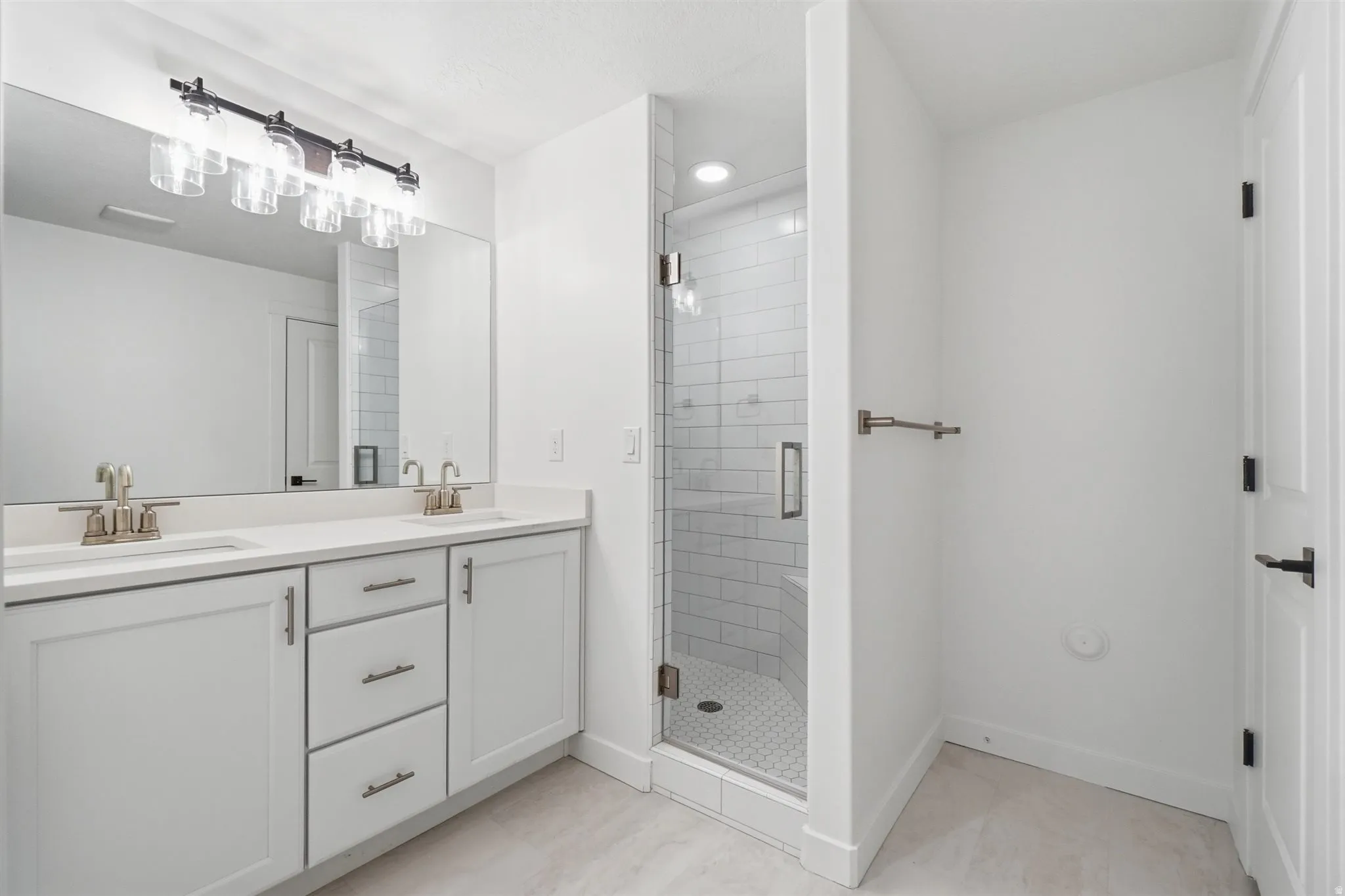 Bathroom featuring a dual vanity with light-toned countertops, white cabinetry, and brushed nickel hardware