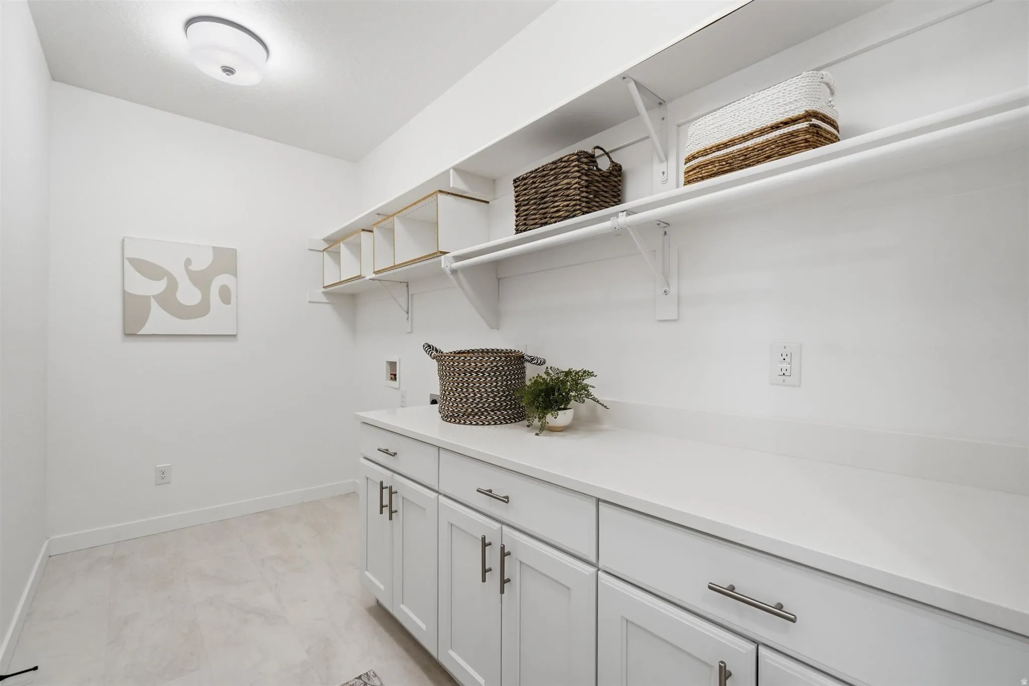Bright utility room featuring white cabinetry, light countertops, and light-toned flooring
