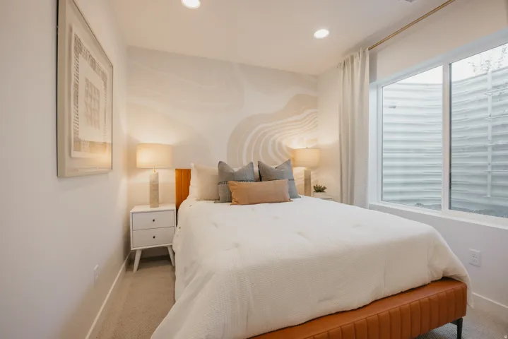 Spacious bedroom featuring recessed lighting, a large egress window, and a decorative wall accent