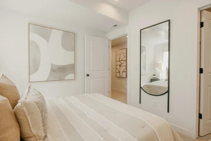 Clean bedroom space featuring light-colored walls and carpet flooring