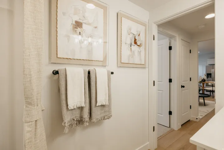 Bright hallway featuring light wood-finish flooring and crisp white walls
