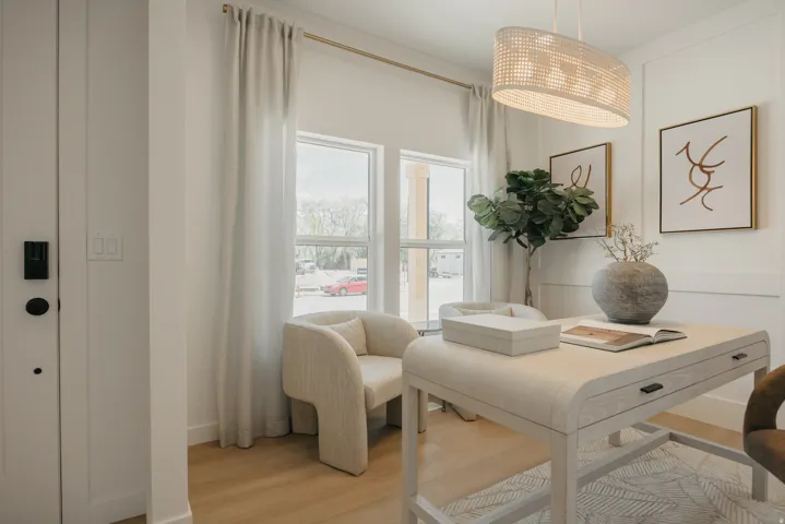 Bright interior room with wood-finish flooring, featuring a statement pendant light fixture and white walls with decorative paneling