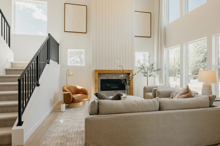 Two-story living area featuring a fireplace with a wood mantel, a shiplap accent wall, and wood-finish flooring