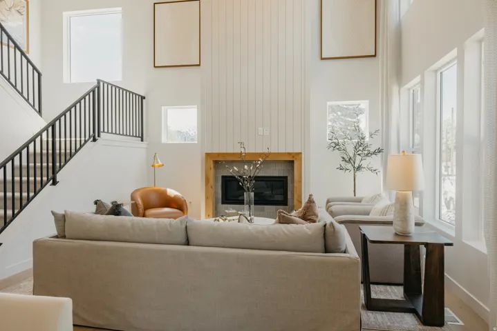 Spacious living area featuring a tall ceiling, a fireplace with a wood mantel, and expansive windows