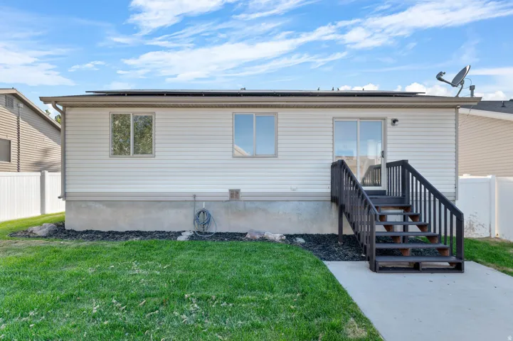 Rear exterior featuring white vinyl siding, a sliding glass door, and exterior stairs with dark wood railings