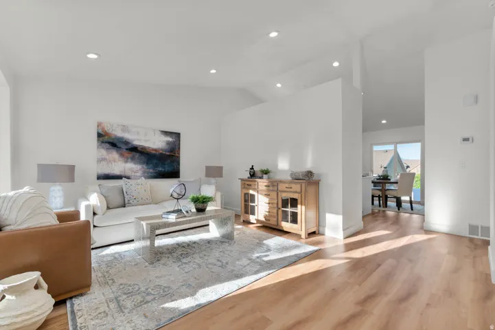 Bright living area featuring wood-finish flooring, vaulted ceilings, and recessed lighting